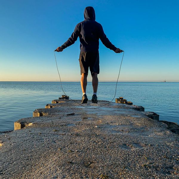 Silhouette of a man stretching against a sunrise, symbolizing energy and vitality.